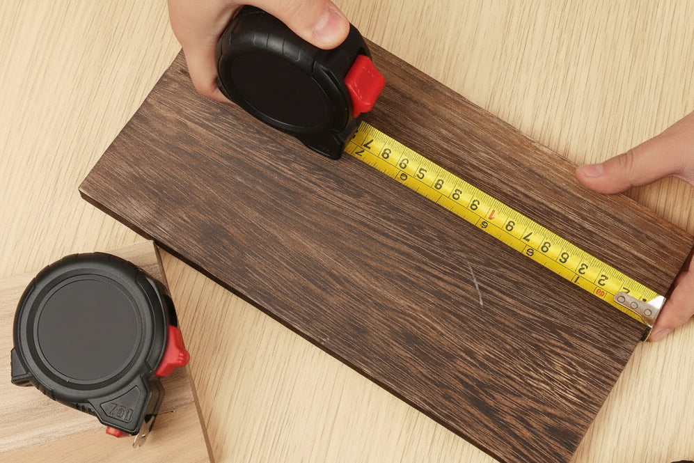 Person measuring wooden planks with a tape measure on a wooden surface
